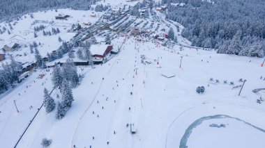 Aerial view of a small resort on top of the mountain in winter season at sunset. Photography was shot from a drone at a higher altitude. Aerial view of a resort in winter at sunset