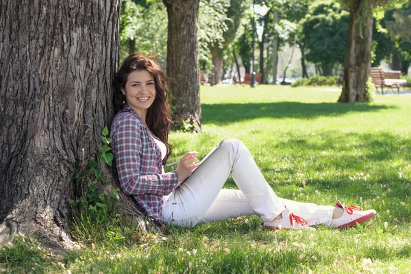 Mädchen sitzt im Park auf dem Gras und zeichnet. — Stockfoto