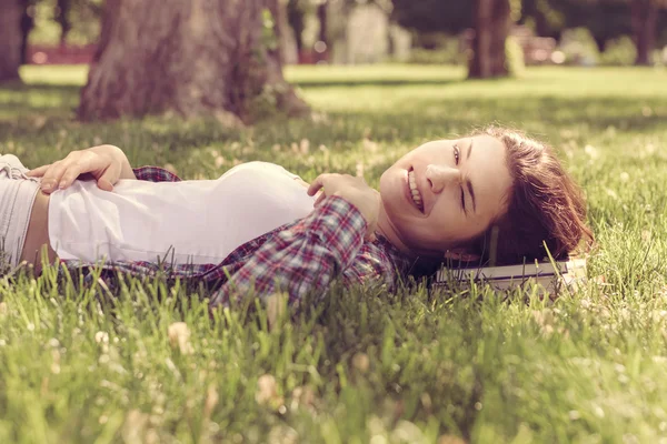 Studentin liegt auf dem Gras im Park und ruht ihren Kopf auf dem Boden — Stockfoto