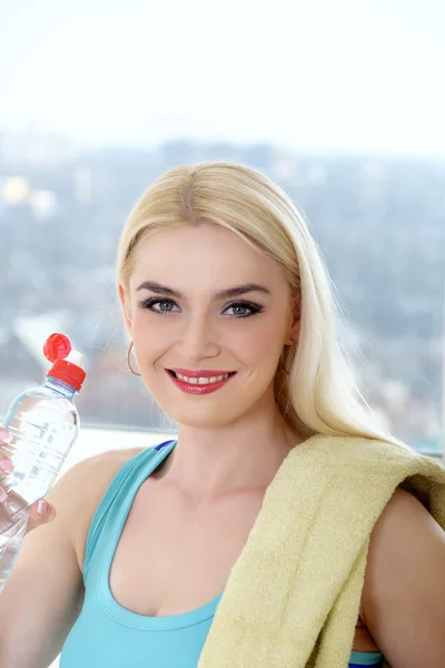 Sportswoman dricker vatten från en plastflaska. — Stockfoto