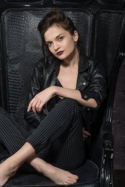 Bir büyük siyah deri sandalyede poz kız.