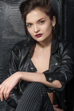 Bir büyük siyah deri sandalyede poz kız.