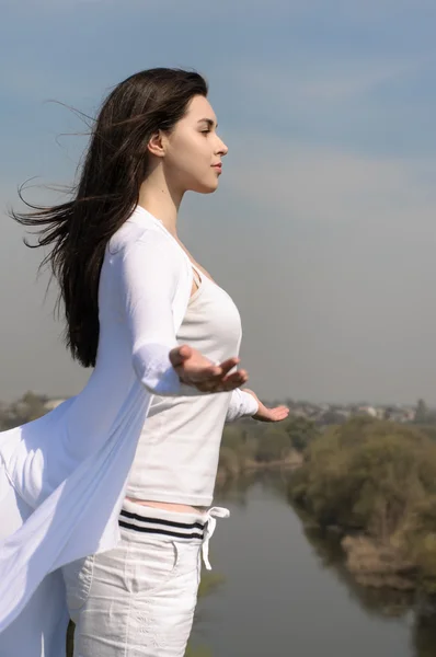 Mädchen meditiert auf einem Hügel vor blauem Himmel. — Stockfoto