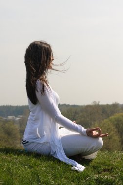 Kız mavi gökyüzü tepe üzerinde yoga yapar.