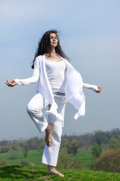 Chica haciendo ejercicio de yoga de pie en una colina — Foto de Stock