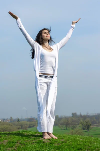 Menina fazendo exercício de ioga em pé em uma colina — Fotografia de Stock