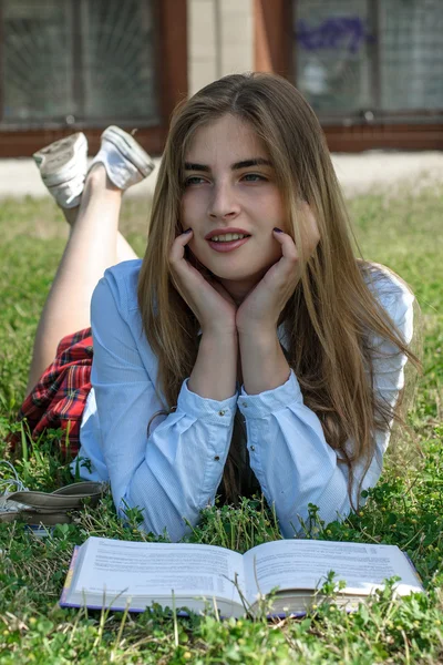 Fille lit un livre tout en étant couché sur l'herbe — Photo