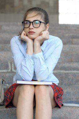 Basamaklarında oturan kız öğrenci 