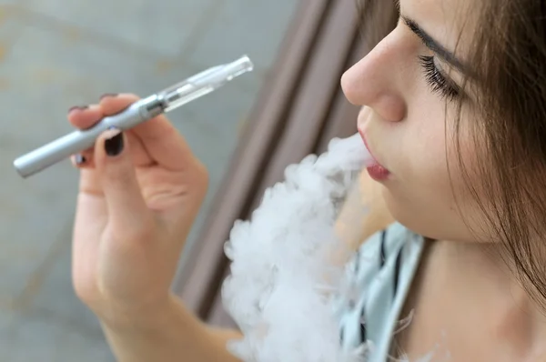 Ragazza fuma una sigaretta elettronica — Foto Stock