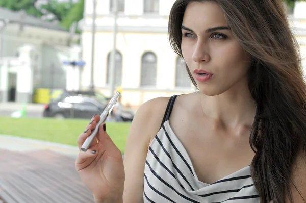 Όμορφη γυναίκα που καπνίζει ένα ηλεκτρονικό τσιγάρο σε εξωτερικούς χώρους — Φωτογραφία Αρχείου