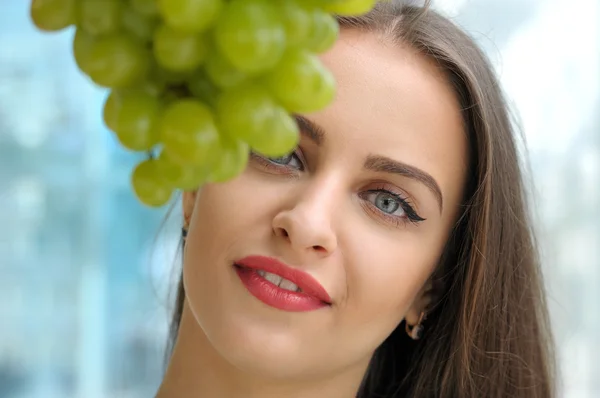 Portrait of a girl behind a bunch of grapes — Stock Photo, Image