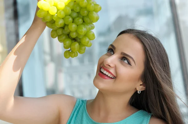 Woman holds a bunch of ripe grapes above her head. — Stock Photo, Image