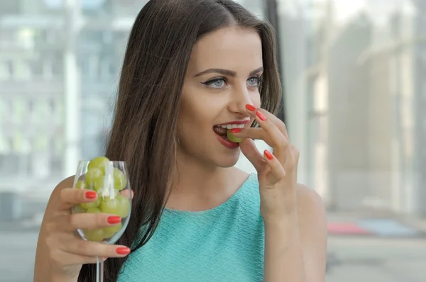 Girl holds a glass with grapes inside. — Stock Photo, Image