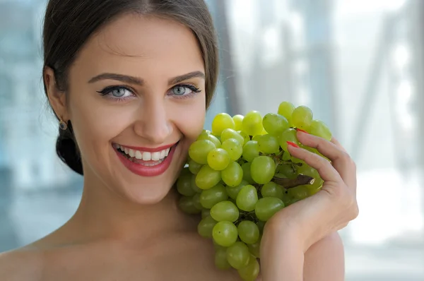 Woman posing with a bunch of grapes and smiling. — Stock Photo, Image