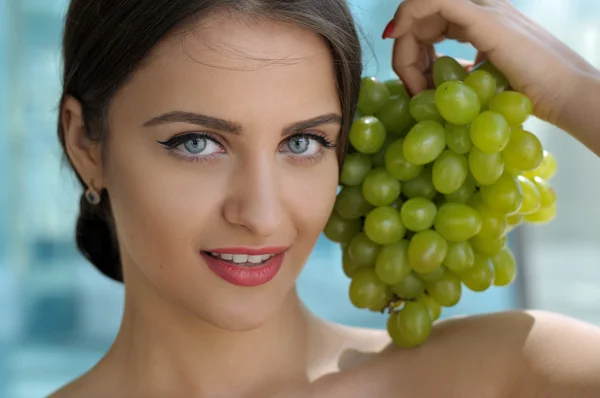 Woman posing with a bunch of grapes and smiling. — Stock Photo, Image