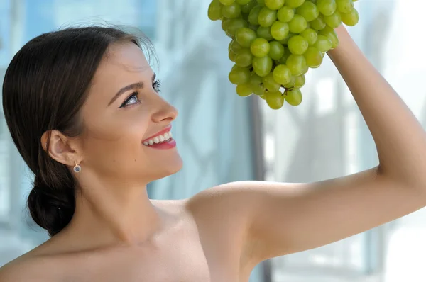 Woman posing with a bunch of grapes and smiling. — Stock Photo, Image