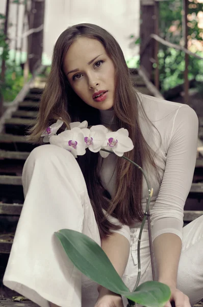 Hermosa chica posando con flor de orquídea — Foto de Stock