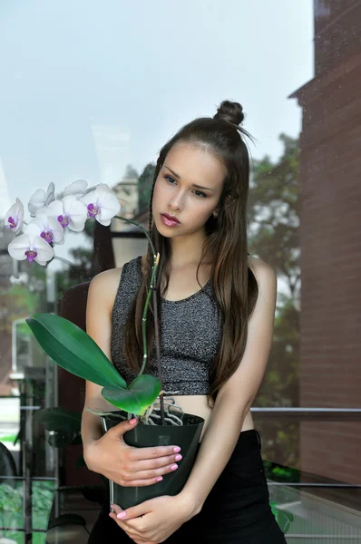 Menina segurando um pote de flor de orquídea em suas mãos — Fotografia de Stock