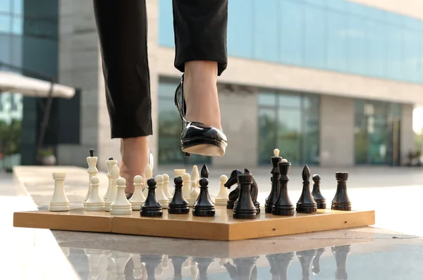 Женские ноги наступают на шахматы — стоковое фото