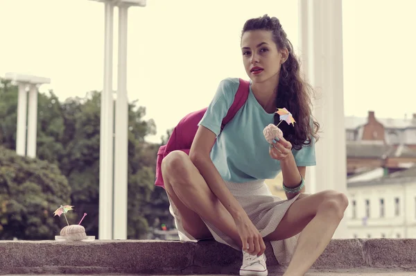 Ragazza si siede sulle scale e tenendo un marshmallow rosa — Foto Stock