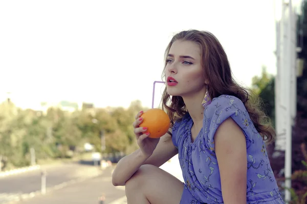 Menina segura uma laranja em suas mãos — Fotografia de Stock