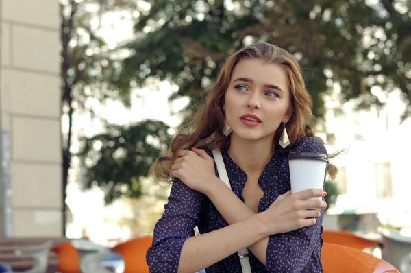 Woman sitting at a table with a paper cup — Stock Photo, Image