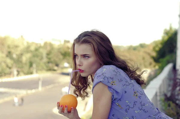 Menina segura uma laranja em suas mãos — Fotografia de Stock