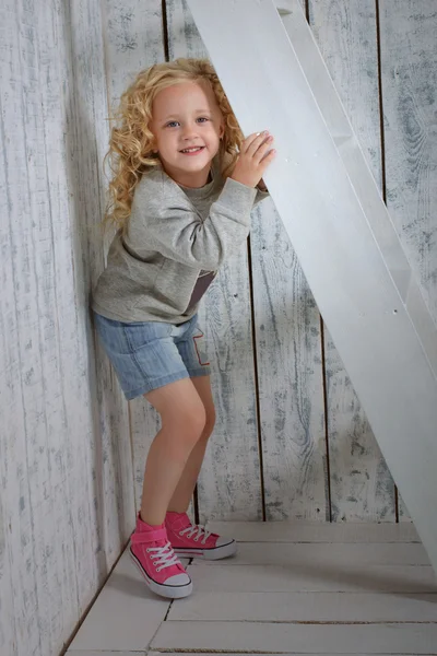 Girl hiding behind the stairs — Stock Photo, Image