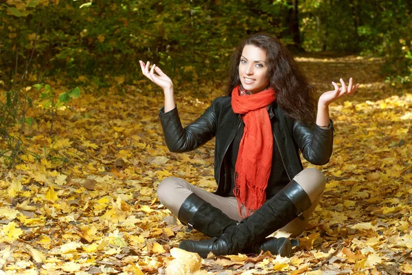 Frau in rotem Schal sitzt im Schneidersitz und hebt die Hände — Stockfoto