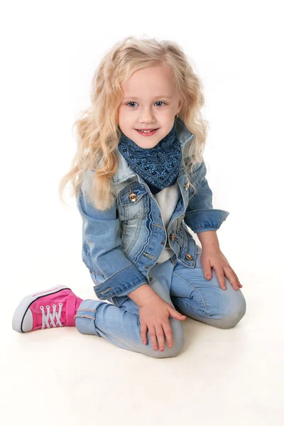 Girl in denim suit and a scarf around her neck sits putting her — Stock Photo, Image