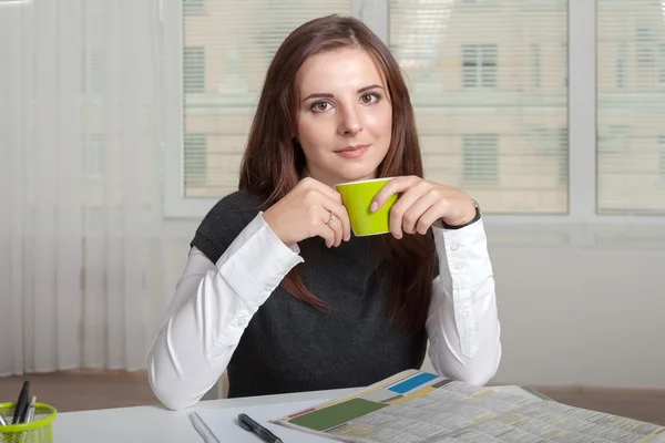 Flicka som håller en kopp grönt nära dess mynning — Stockfoto