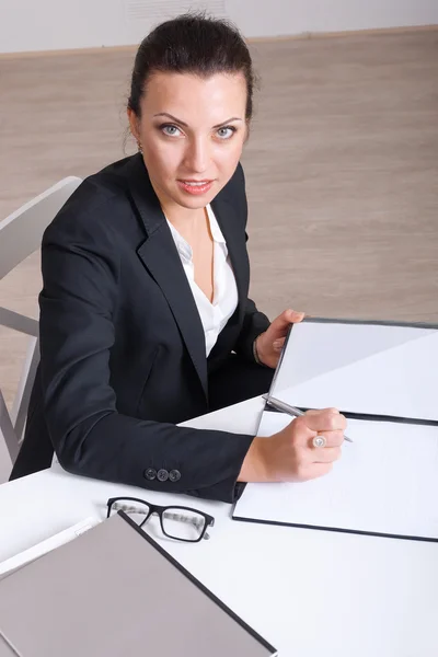 Pracownik biurowy kobieta podpisuje dokumenty siedzi przy stole — Zdjęcie stockowe