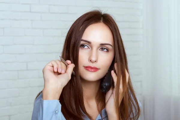 Meisje spreekt door telefoon en doelstellingen pen zoals een dart — Stockfoto