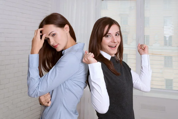 Two women in formal clothes standing back to back against the wi — Stock Photo, Image