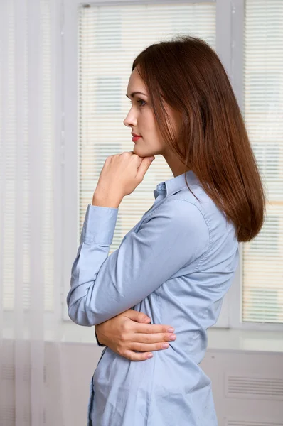 Girl is standing sideways attaching her hand to her chin — Stock Photo, Image