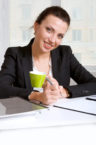 Dívka v vypadající dokumenty, pití kávy a s úsměvem — Stock fotografie