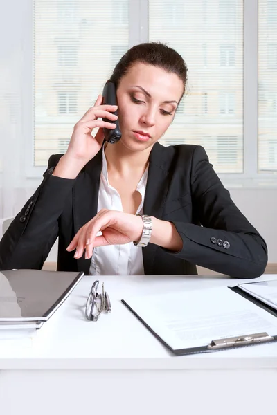 Female talking on the phone and looking at wristwatch — Stock Photo, Image
