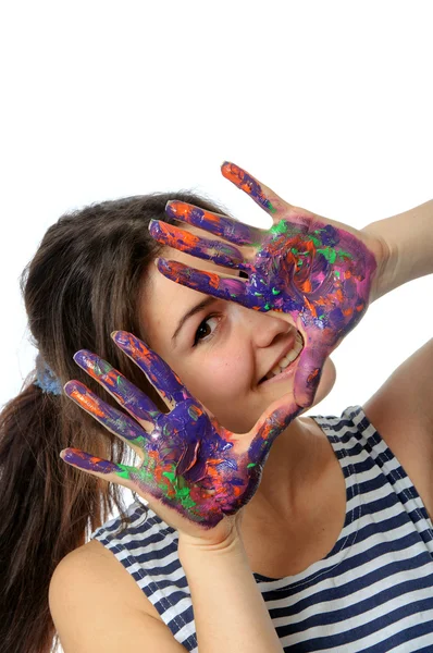Женщина смотрит на свои руки, раскрашенные в красочную краску — стоковое фото