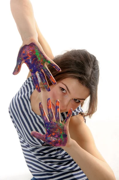 Девушка в полосатой рубашке смотрит на ладони, раскрашенные в разные цвета — стоковое фото