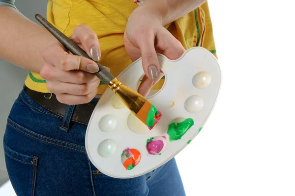 Girl artist holding a palette with paints and brush Stock Picture