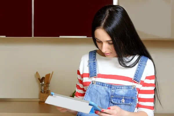 Brunett hemmafru läsning på tablett recept i köket — Stockfoto