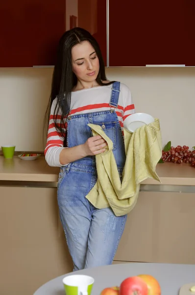 Hausfrau brünett in home clothes wischt untertasse. Stockfoto