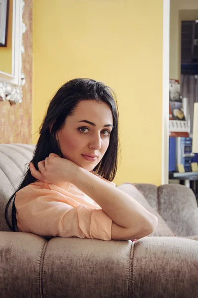 Girl in casual clothes sitting on a sofa slightly sad — Stock Photo, Image