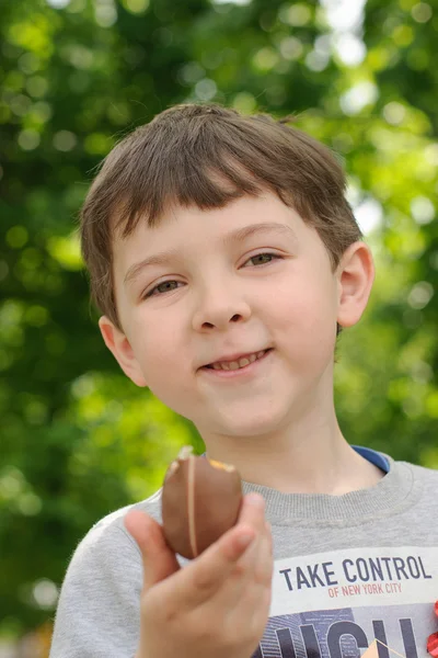 Il ragazzo mangia uova di cioccolato e sorride — Foto Stock
