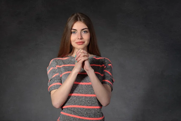 Vrouw toont geloof tegen de donkere achtergrond — Stockfoto