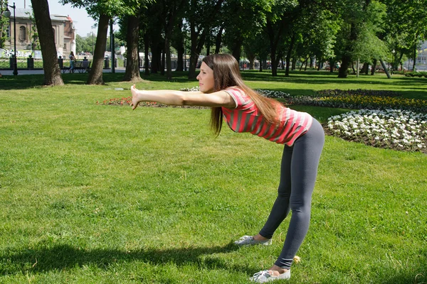 Girl doing exercise tilts forward outside — Stock Photo, Image