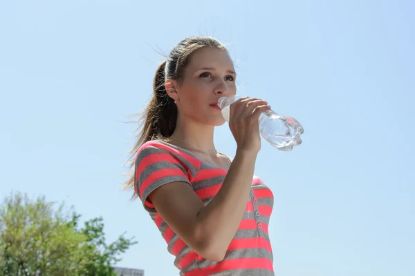 Holka pije vodu proti obloze — Stock fotografie