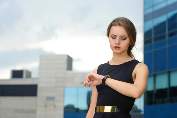 Mujer de negocios mira cuidadosamente su reloj de pulsera — Foto de Stock