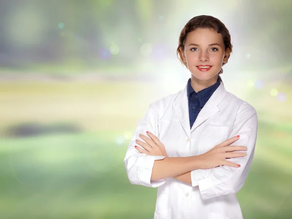 Woman doctor in a white coat smiling with her arms crossed — Stock Photo, Image