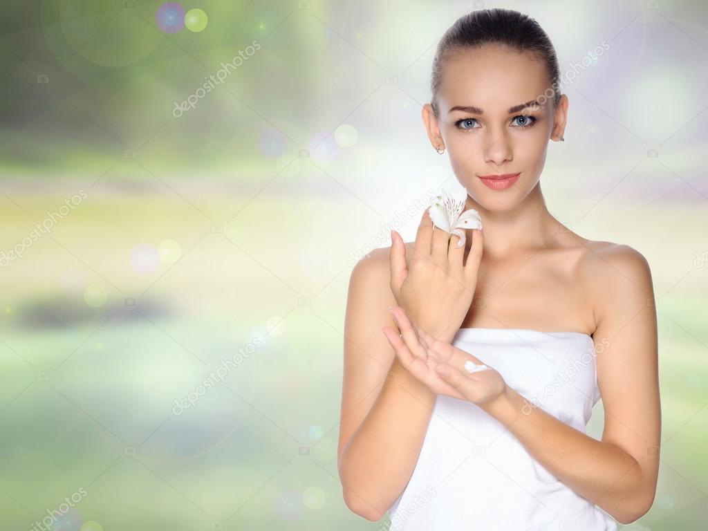 Girl holds a lily in one hand and the cream in the other